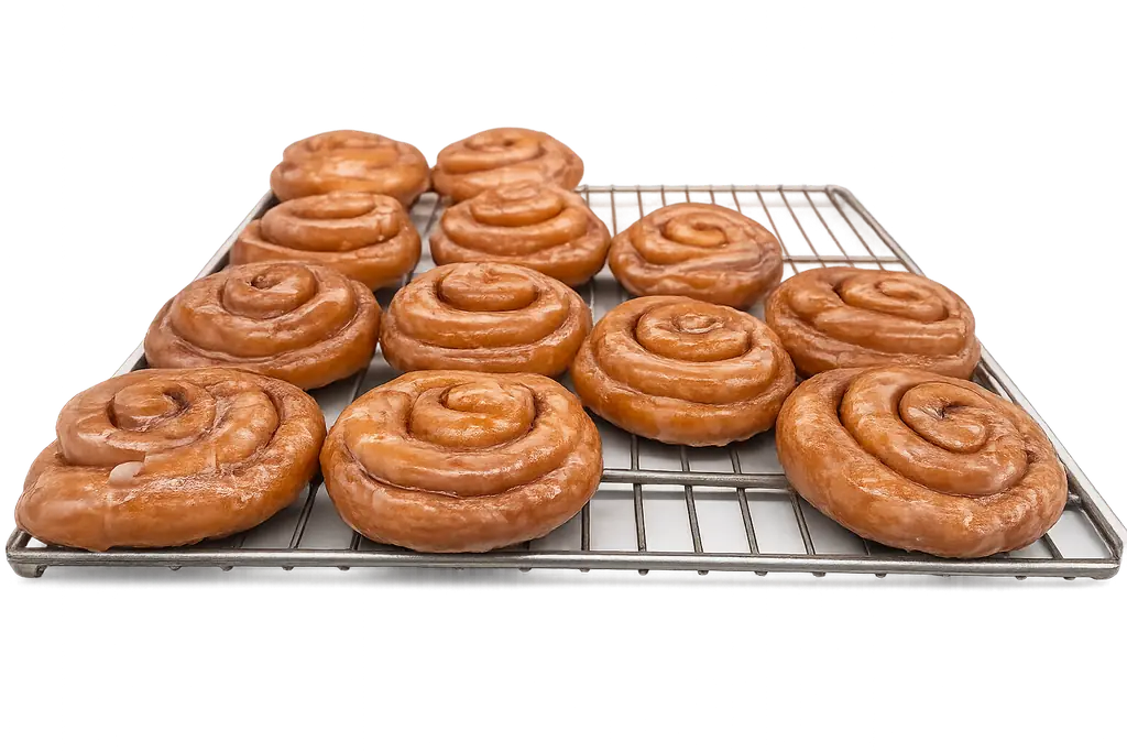 Glazed cinnamon rolls arranged on a wire cooling rack at Atlanta Donuts.